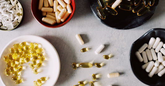Frasco de multivitamínico para mujeres mayores de 40 con cápsulas derramadas sobre una superficie clara, representando el mejor multivitamínico para mujeres over 40.