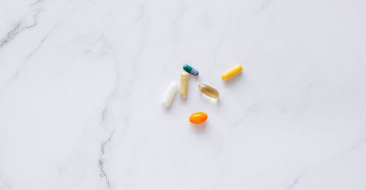Cápsulas de biotina para el cabello y uñas sobre una superficie clara, representando suplementos de belleza.
